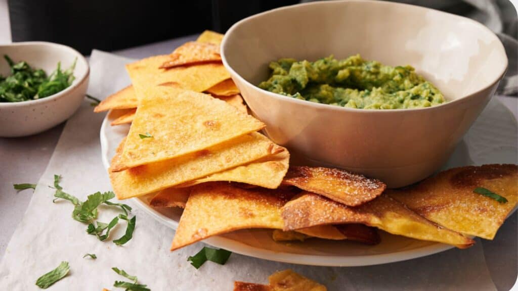 Guacamole and chips on a plate with a bowl of guacamole.