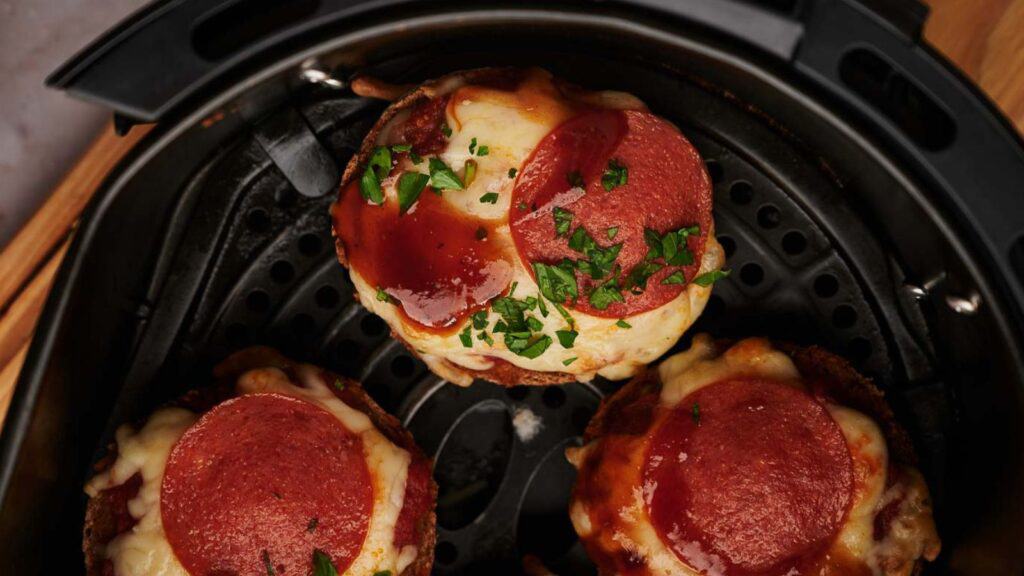 Three pepperoni pizzas in an air fryer.