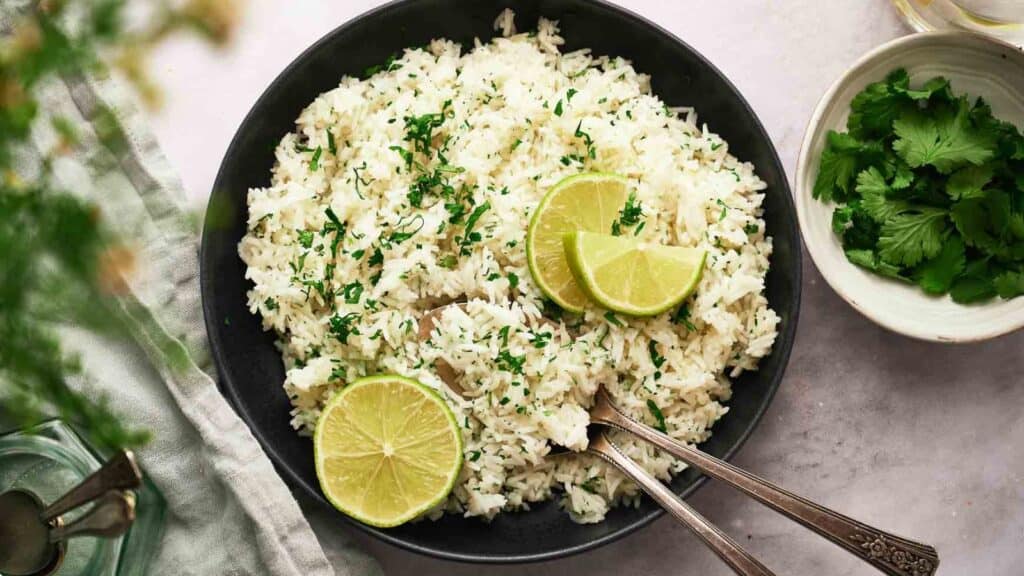 A bowl of rice with lime slices and parsley.