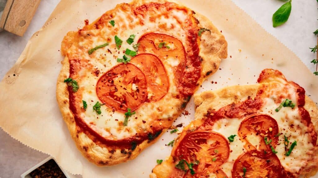 Two slices of pizza with tomatoes and herbs.