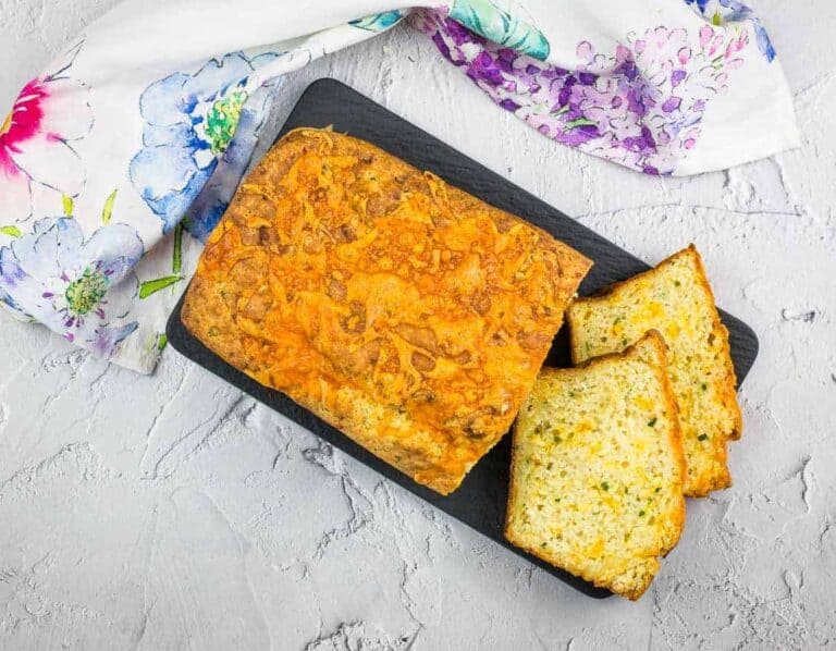 A half-cut loaf of Potato Cheese Bread on a platter.