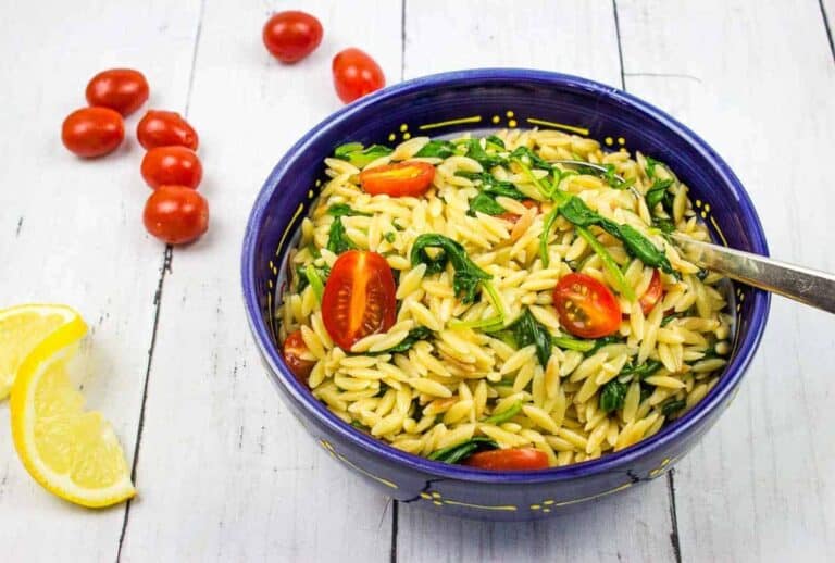 A bowl of Creamy Spinach Orzo in a blue bowl with yellow dots.