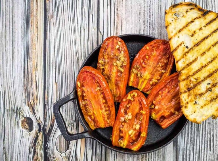 Smoked Tomatoes in a skillet on a wooden table.