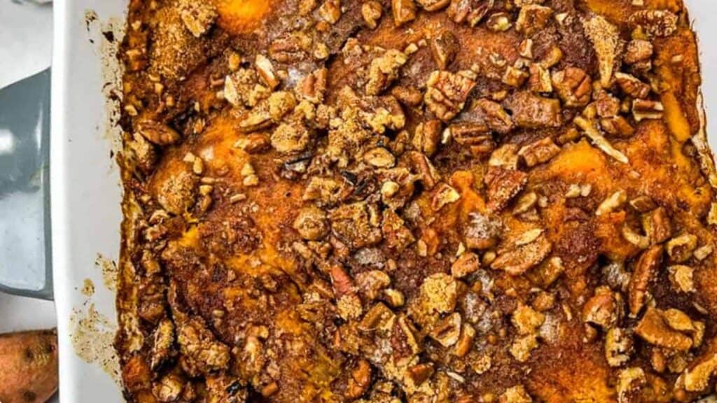 Sweet Potato Casserole in a white dish with nuts on top.