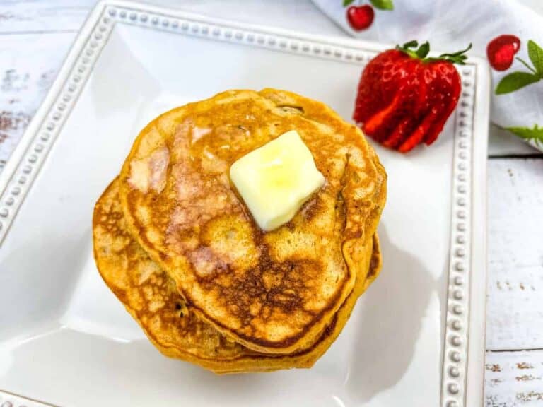 Sweet Potato Pancakes with butter and strawberries on a white plate.