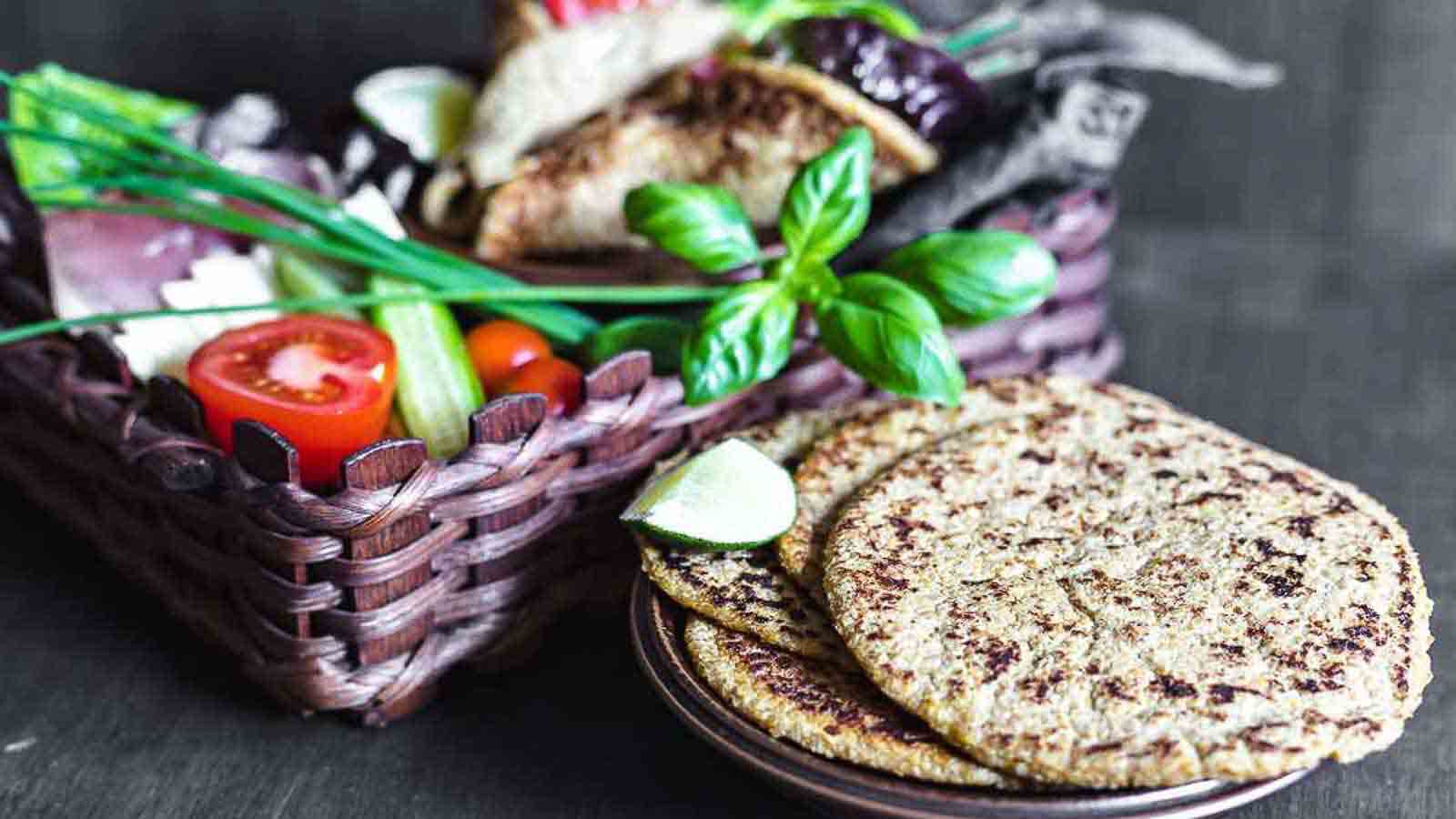 Flaxseed Wraps on a tray with brown basked with veggies behind. 