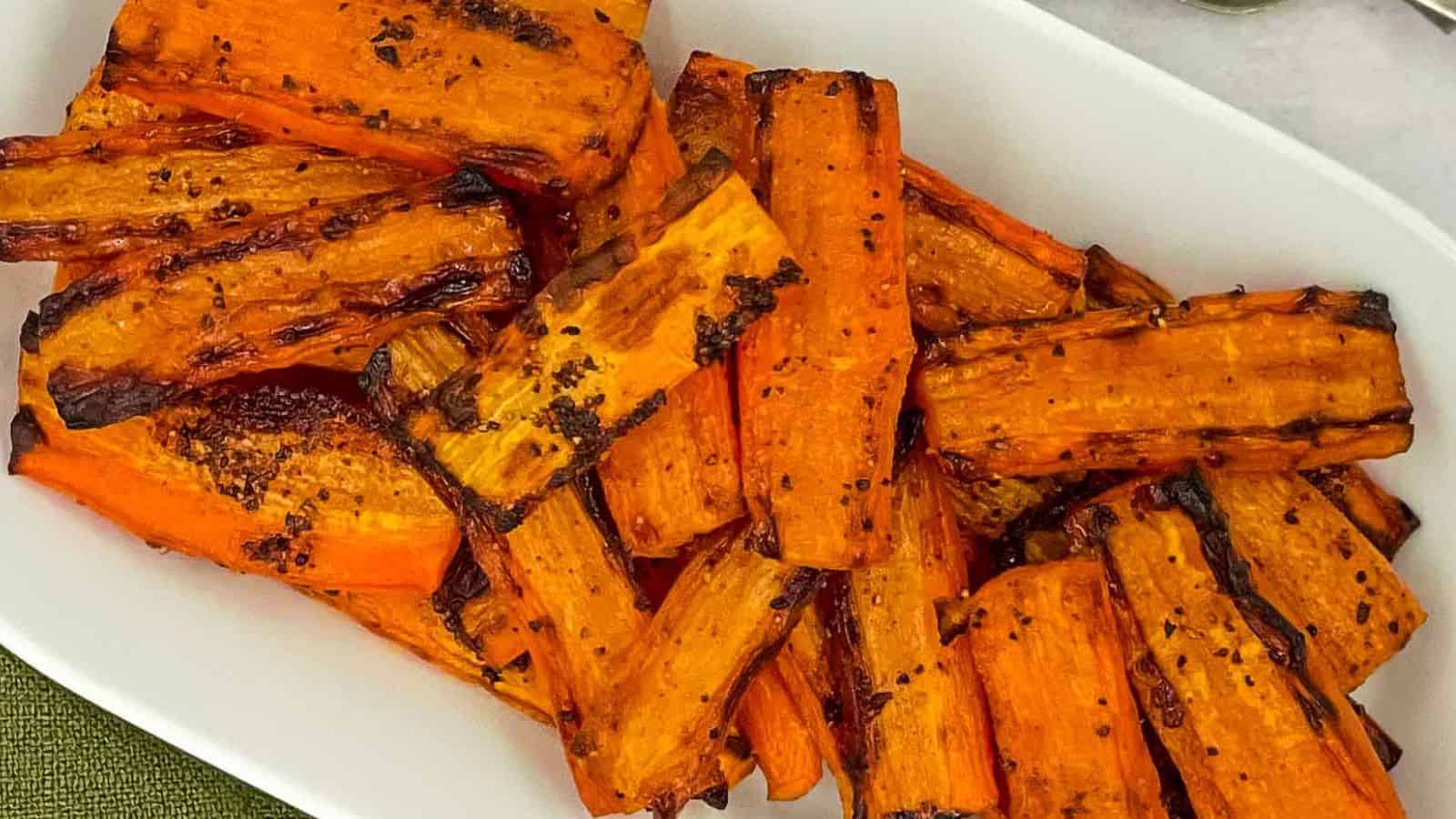 Roasted carrots on a white plate with a fork.