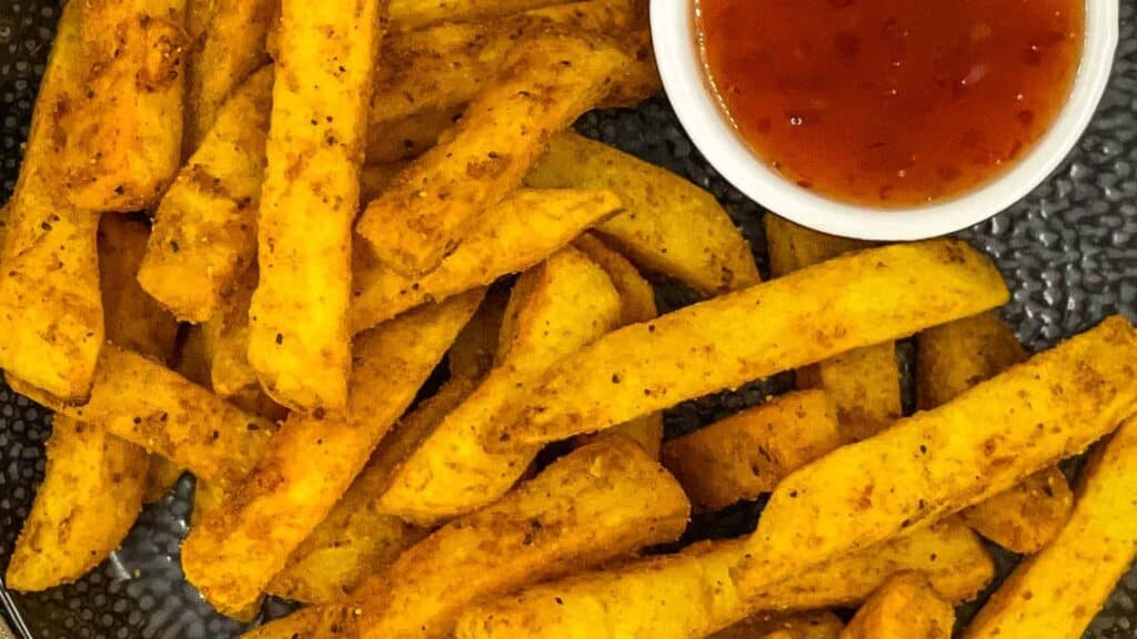 A plate of french fries with a dipping sauce.