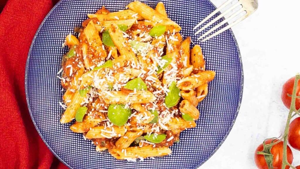 A plate of pasta with tomatoes and parmesan cheese.