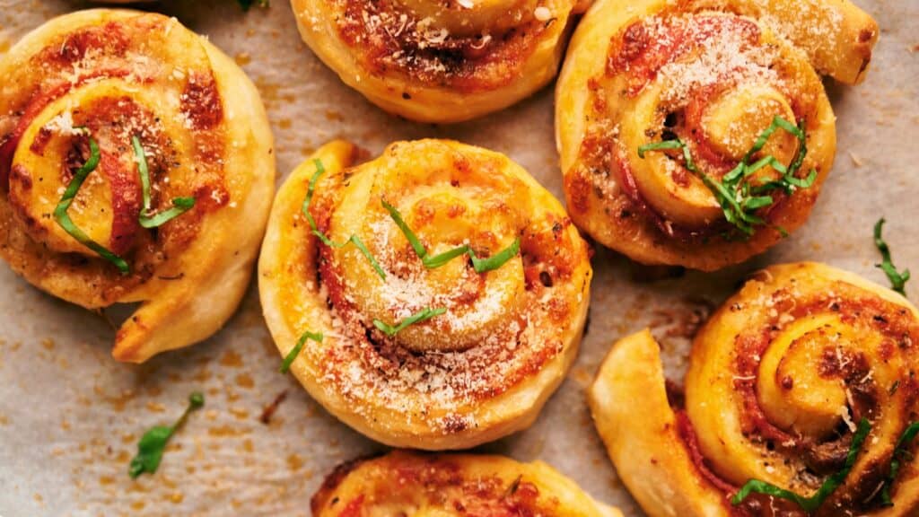 A tray of pizza rolls with cheese and herbs on it.