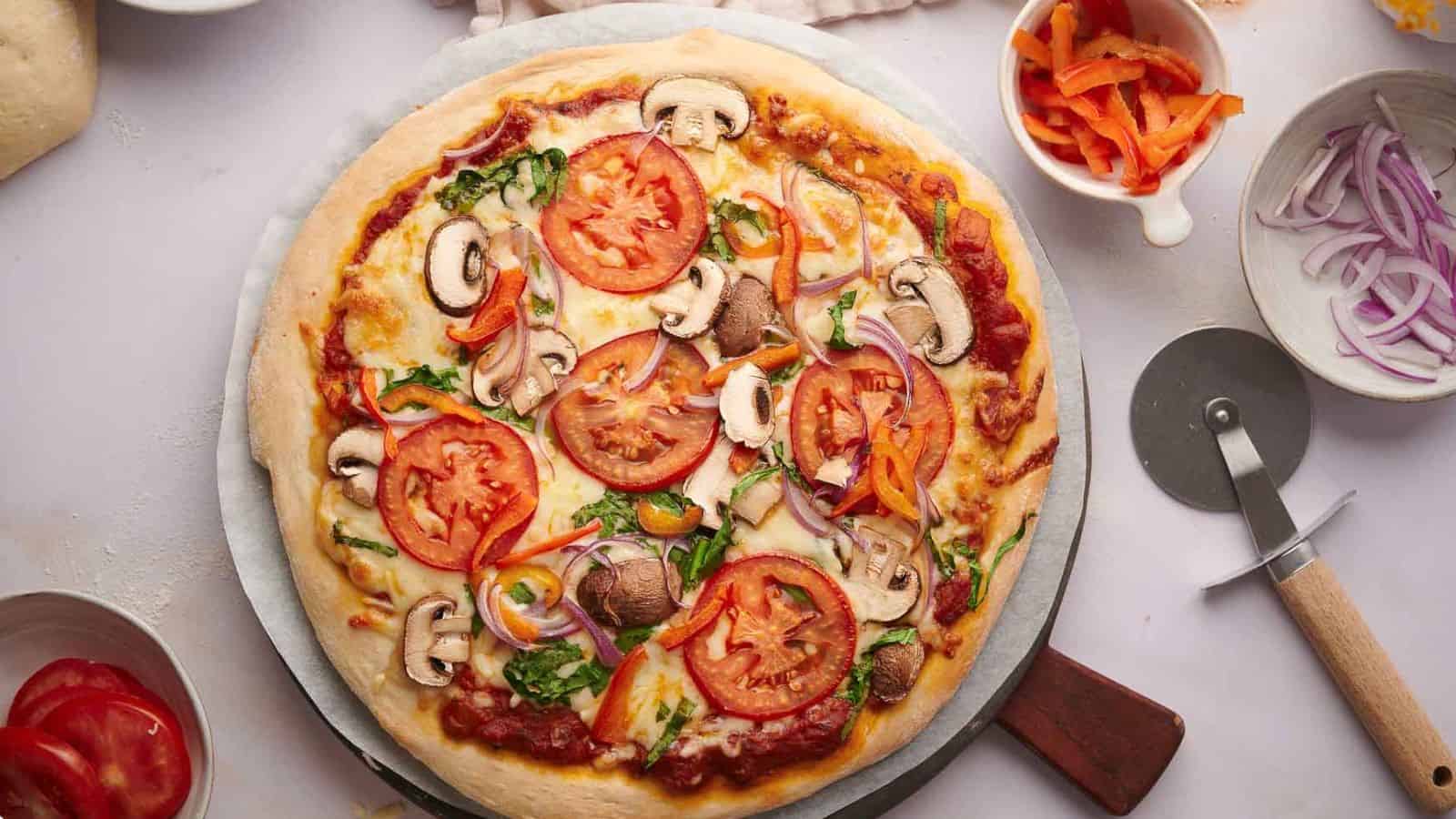 A pizza with tomatoes, onions and mushrooms on a plate.