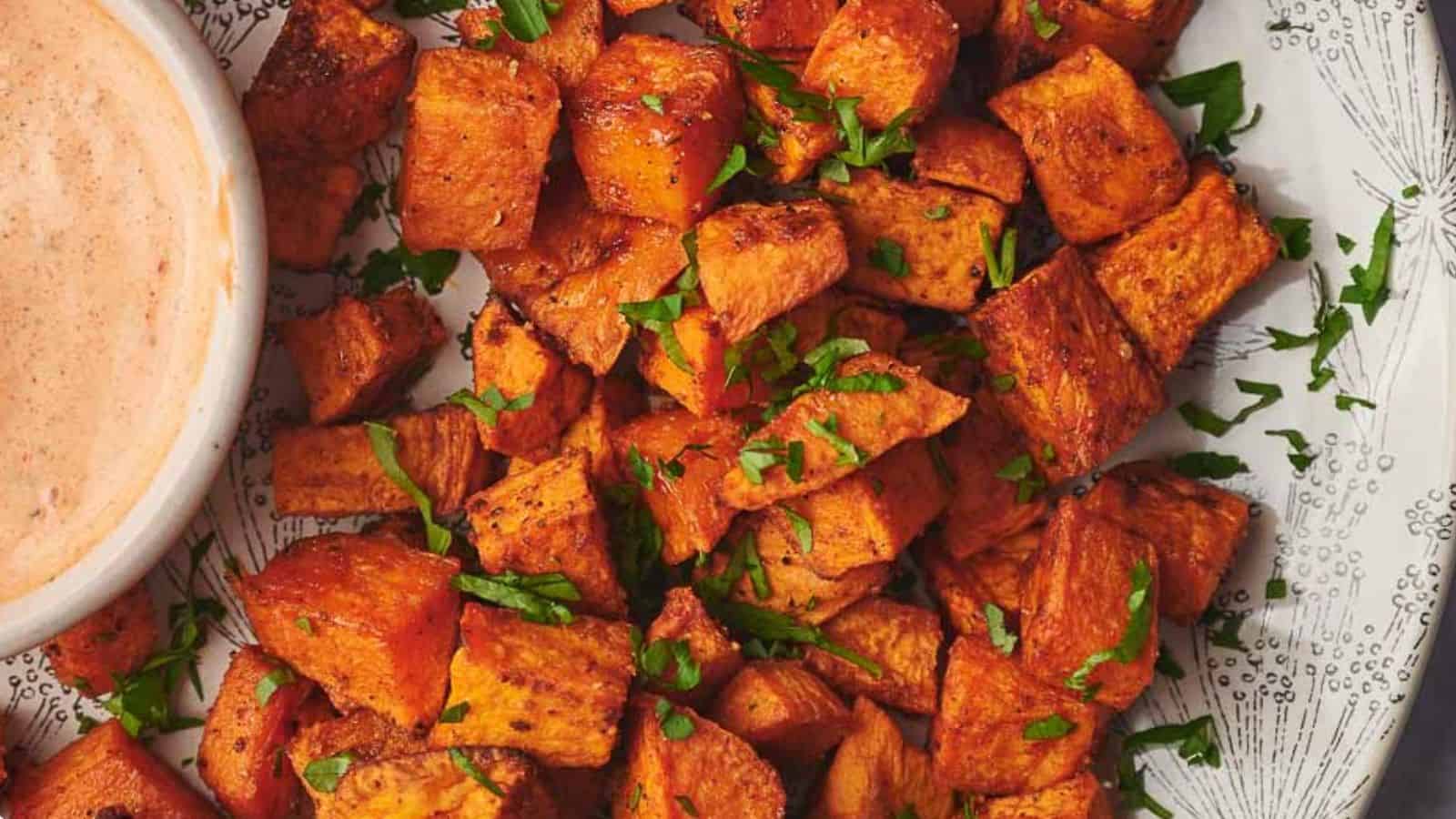 Sweet potato cubes on a plate with a dipping sauce.