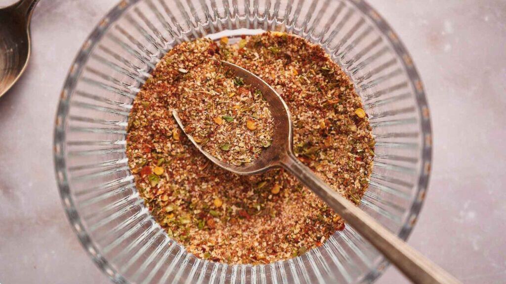 A bowl of seasoning with a spoon in it.