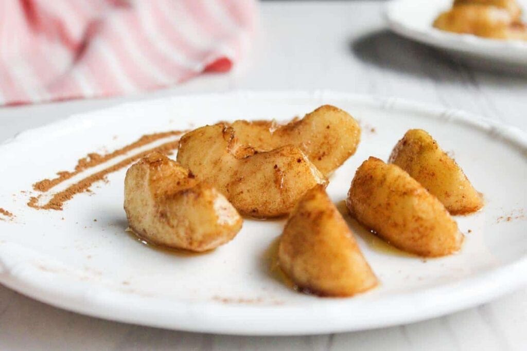 Sliced apples on a plate with cinnamon and sugar.