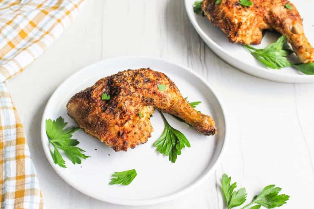 Two plates of grilled chicken on a wooden table.