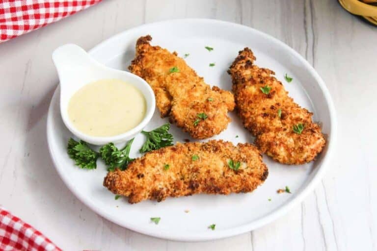 Fried chicken tenders on a white plate with dipping sauce.