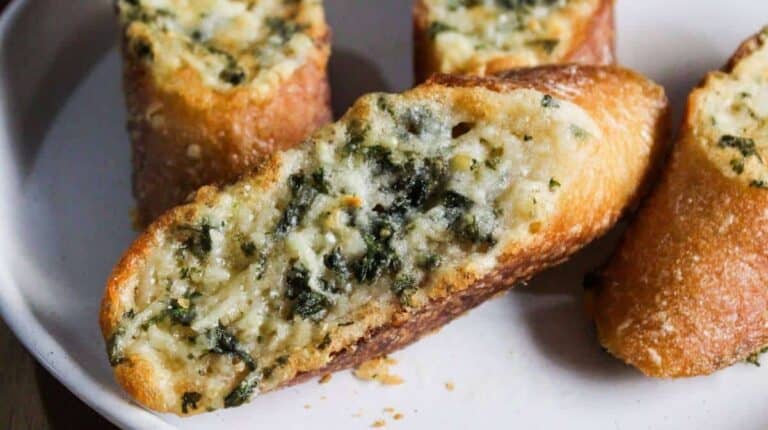 Two slices of bread with cheese and spinach on a plate.