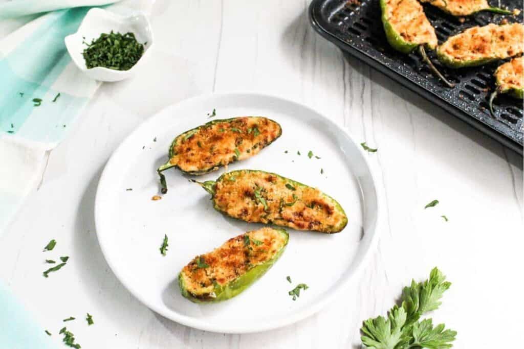 Stuffed jalapenos on a white plate with parsley.