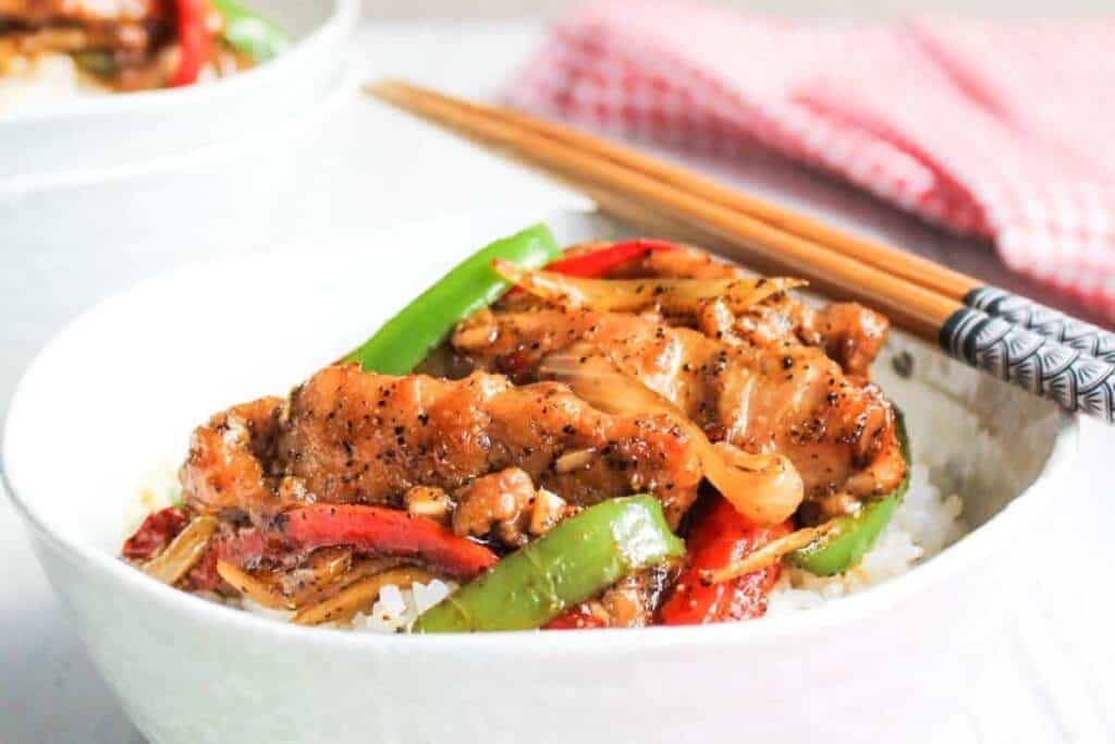 Chinese chicken stir fry in white bowls with chopsticks.