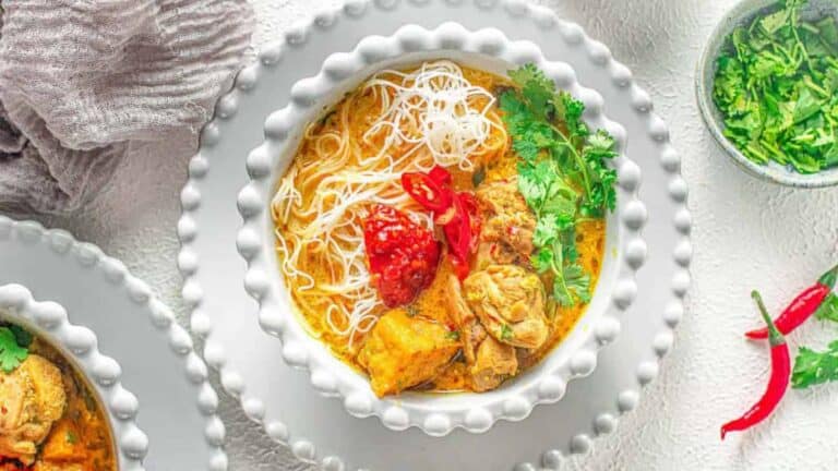 Chicken curry soup with noodles in white bowls on a table.