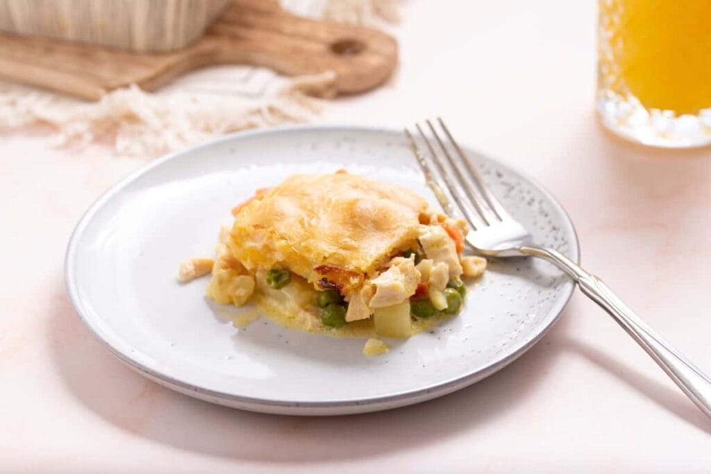 A plate with a piece of chicken and vegetable pie on it.