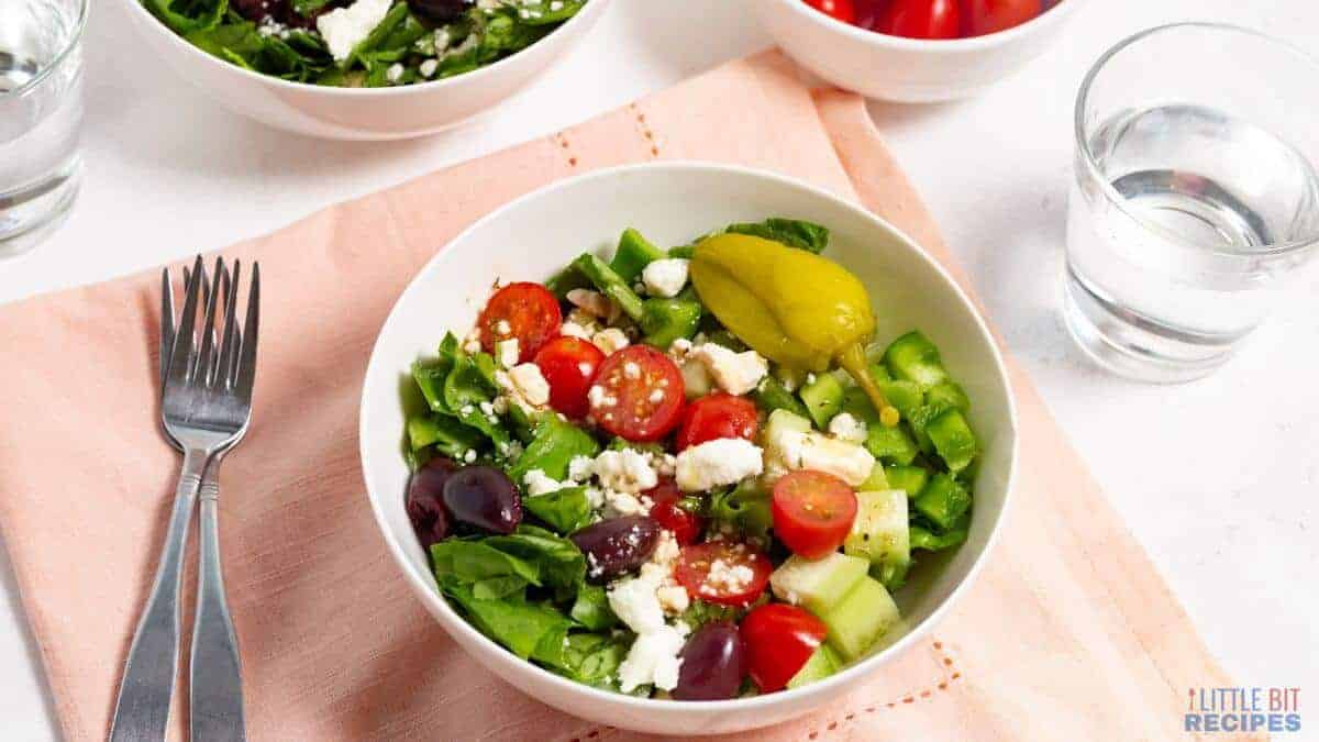 A colorful chopped Greek salad in a white bowl.