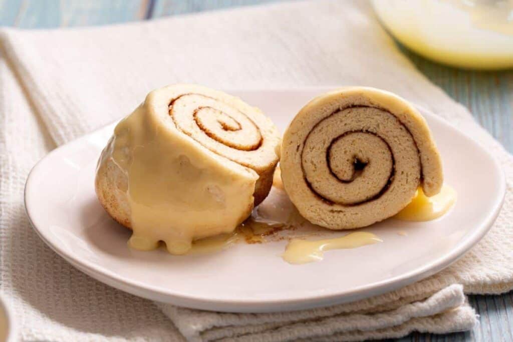 Two cinnamon rolls on a plate with icing.