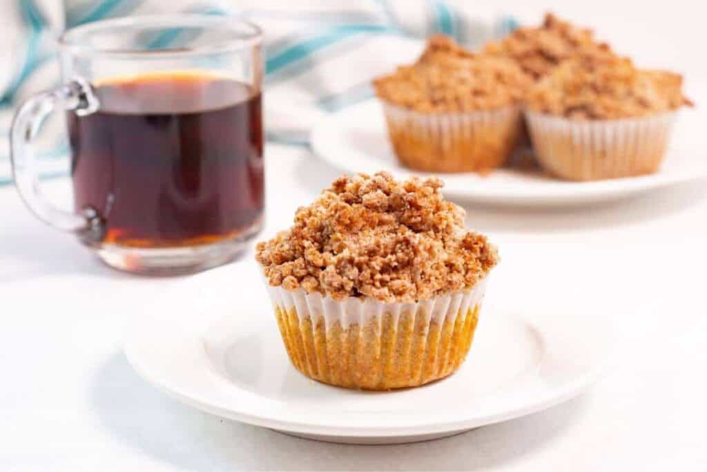 Pumpkin muffins on a plate next to a cup of coffee.