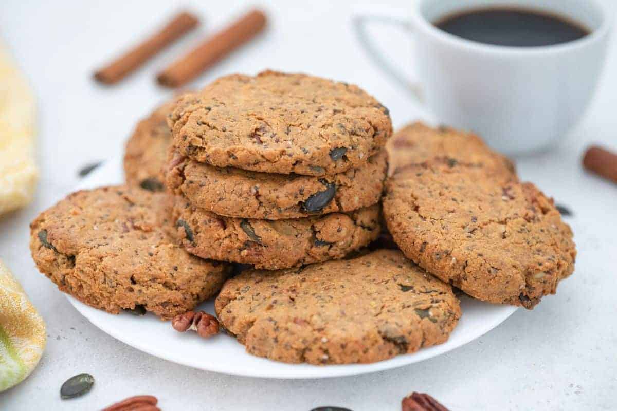 Seed and nut butter cookies on plate served with coffee.
