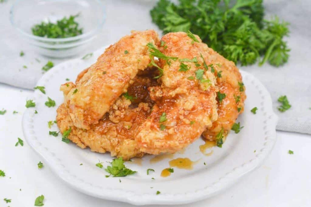 Fried chicken on a white plate with parsley.