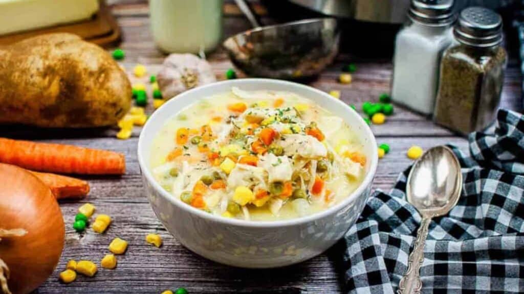 Instant pot chicken pot pie soup in a white bowl with carrots and potatoes.