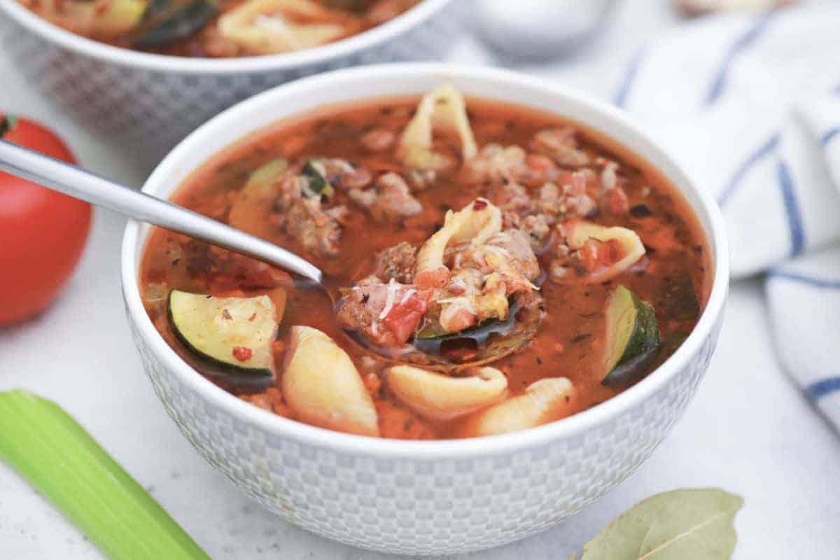 Minestrone Soup with Sausage in white bowl with spoonful.