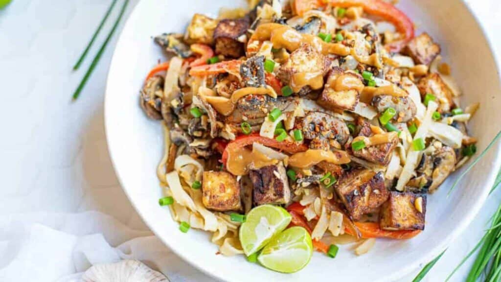 A bowl of noodles with mushrooms and tofu.
