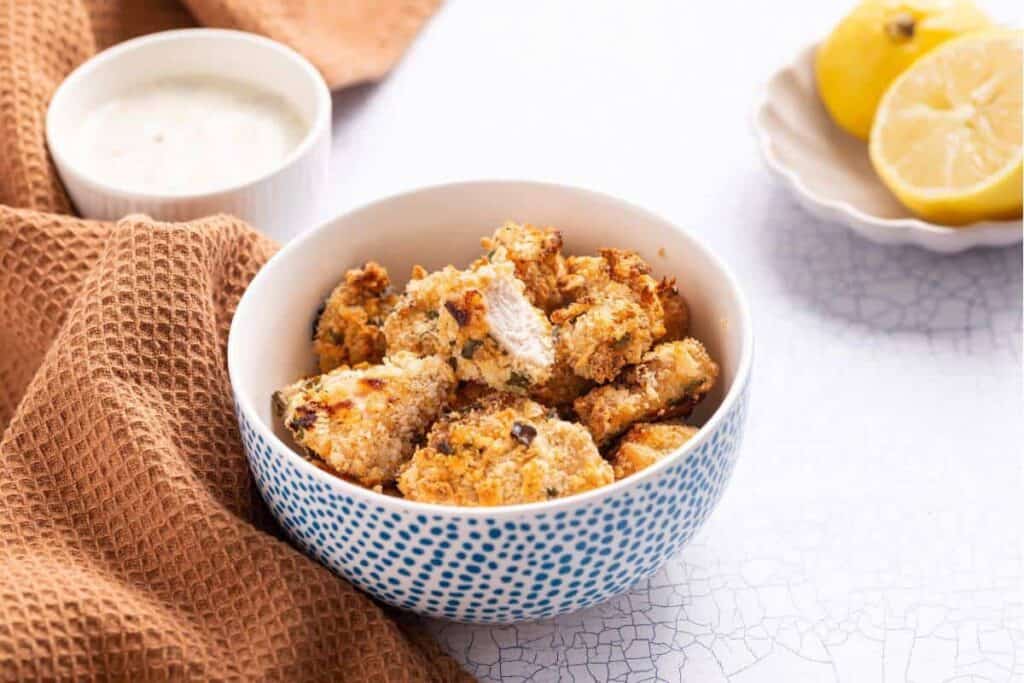 Fried chicken in a bowl with a bowl of dipping sauce.