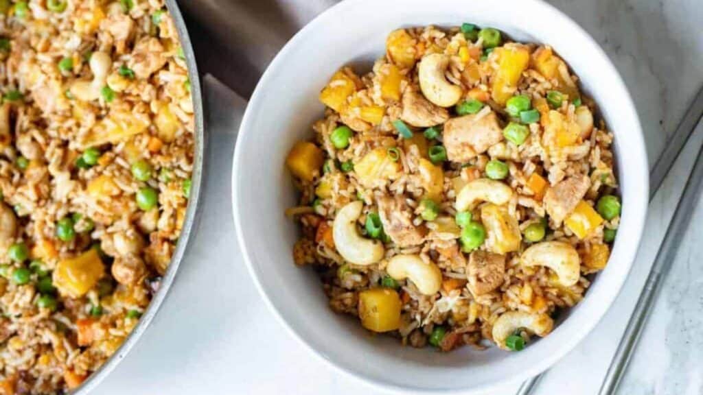 Two bowls of fried rice with peas and carrots.