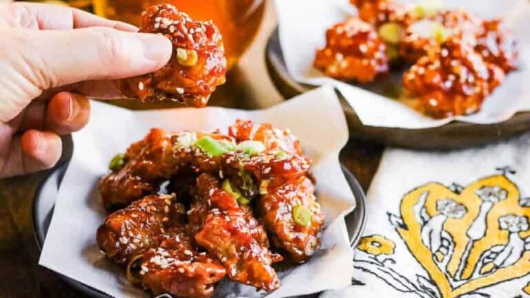 Low angle shot of korean fried chicken with a hand holding a piece of the chicken.