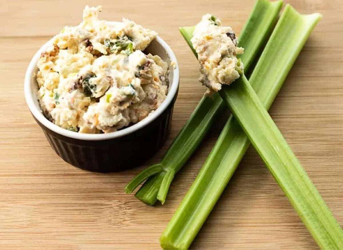 A bowl of celery salad with celery sticks next to it.