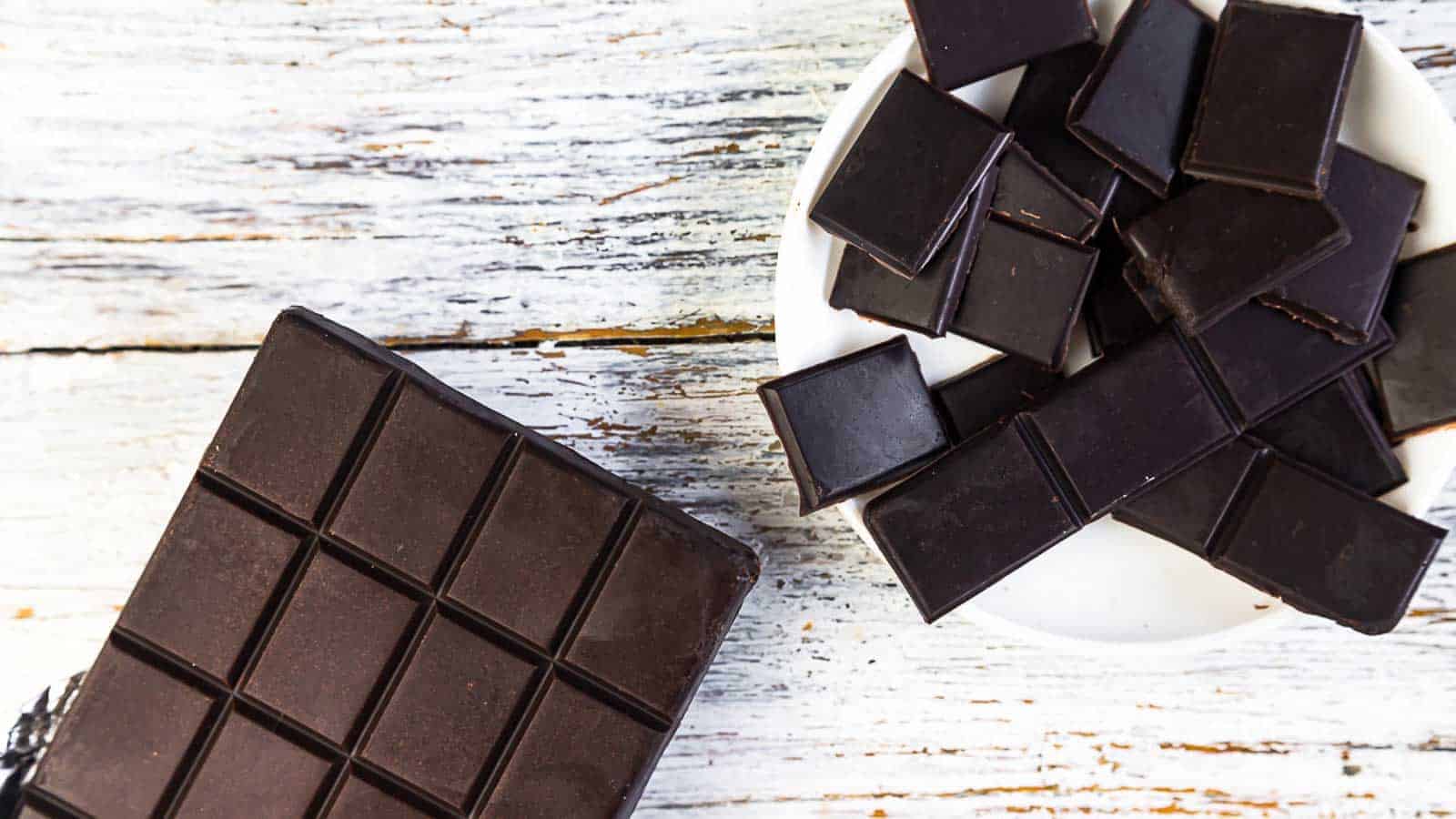 Sugar-Free Dark Chocolate Bar on a table with broken pieces in a bowl. 