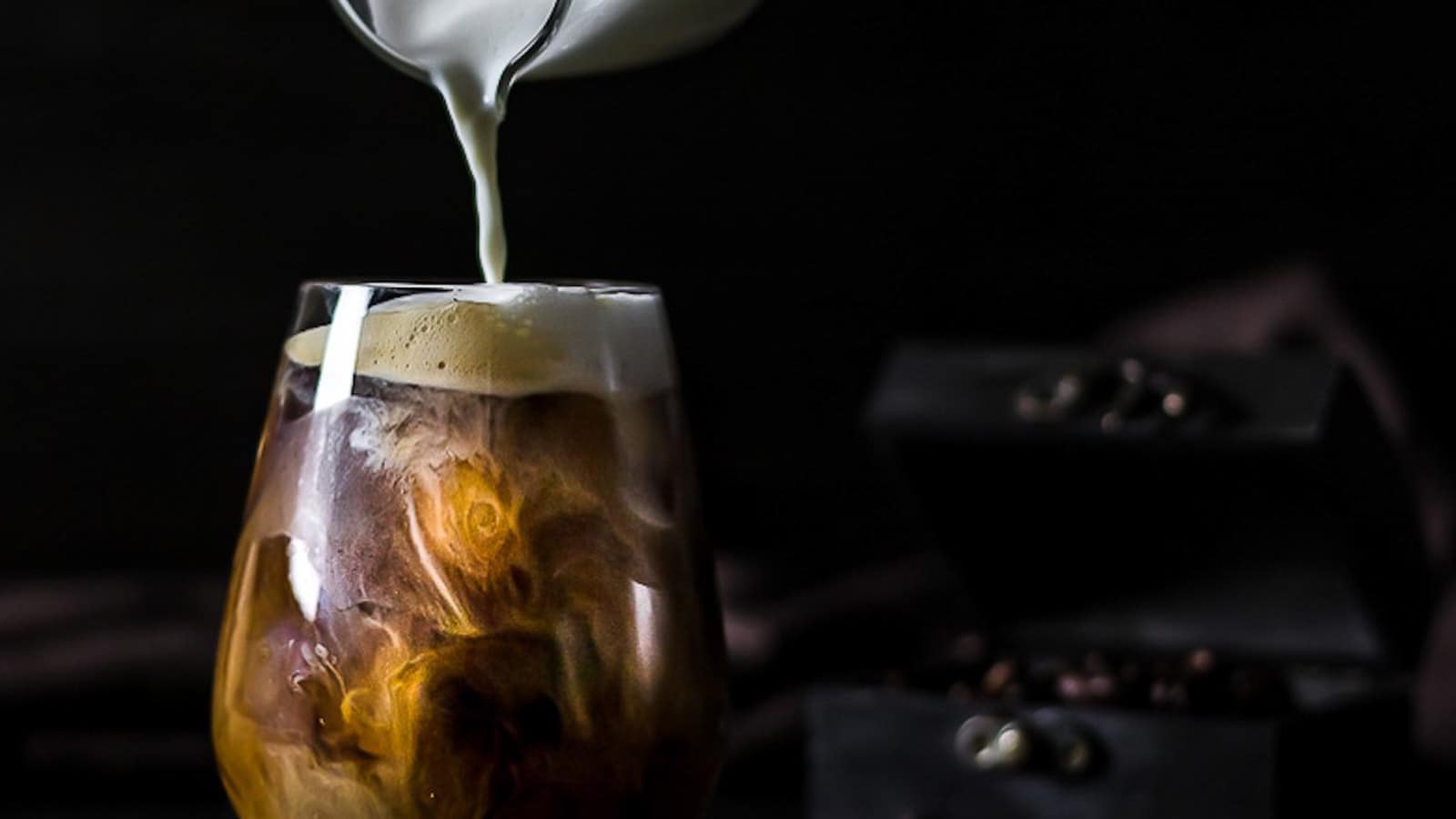 Milk being poured into a glass of Cold Brew Coffee.