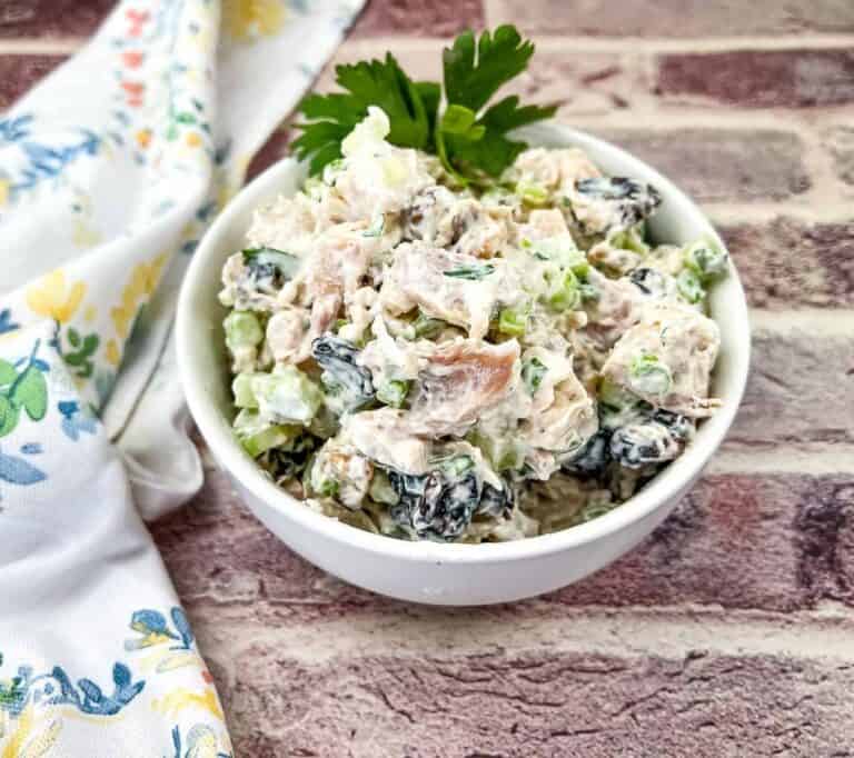 A white bowl of tuna salad on a brick wall.