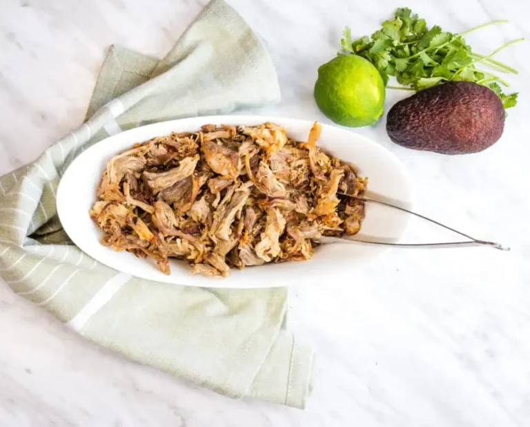 Al Pastor Carnitas in a white bowl with tongs.