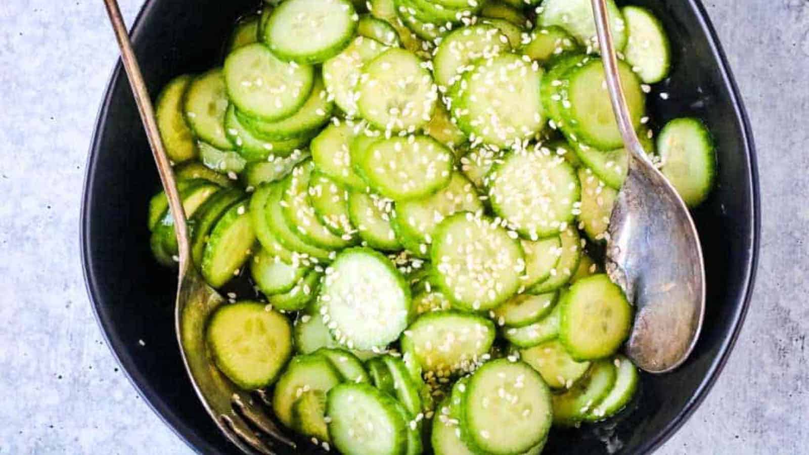 A black bowl of Japanese cucumber salad garnished with sesame seeds.