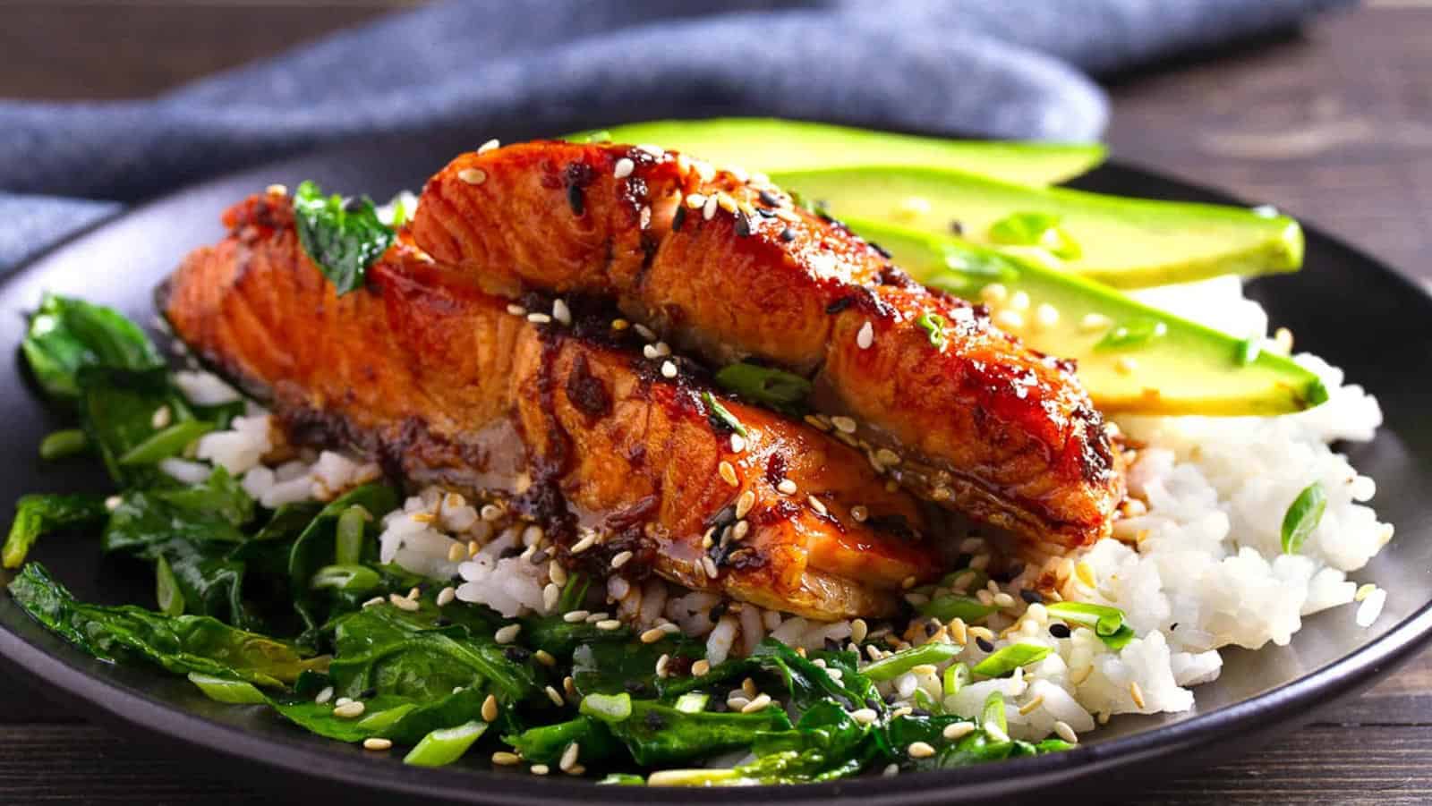 Miso glazed salmon on a plate with rice and spinach.