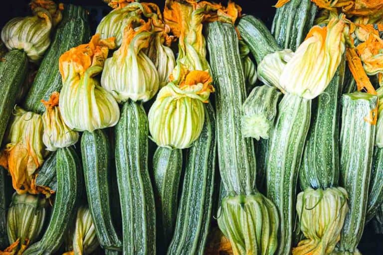 A bunch of squash flowers are piled up on a table.