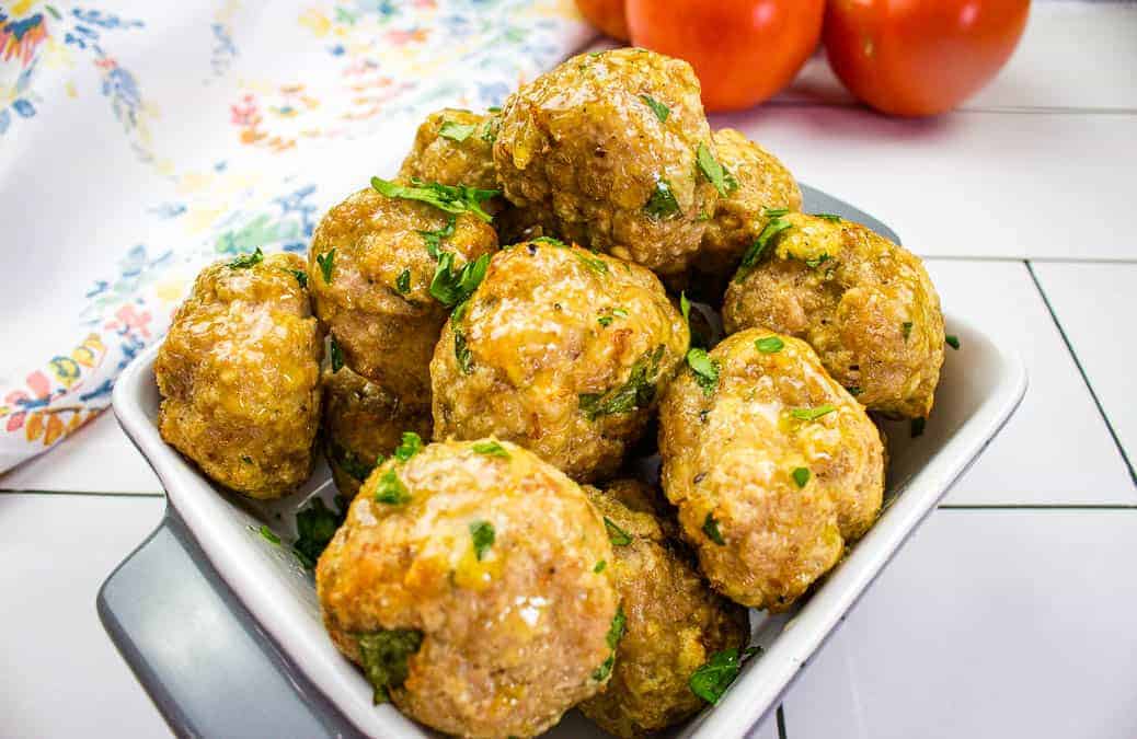 A closeup of air fryer Turkey Meatballs with tomatoes in the background.