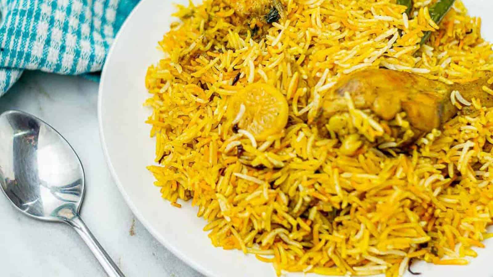 Chicken biryani in a white bowl with a spoon.