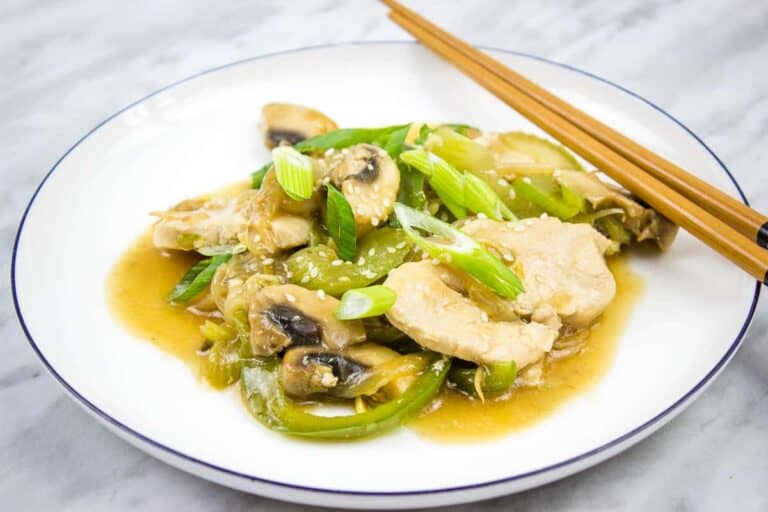 A white plate with chicken and mushrooms in a sauce.