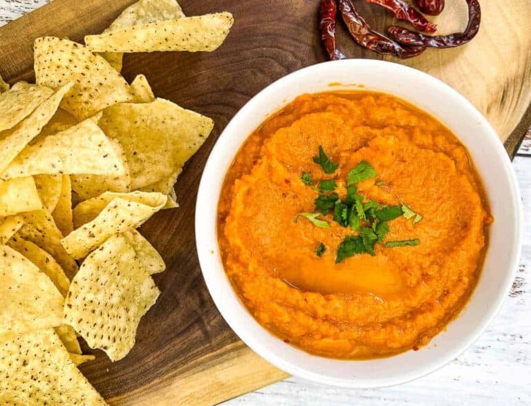 Chile de Arbol Salsa on wooden board with chips and chilies nearby.