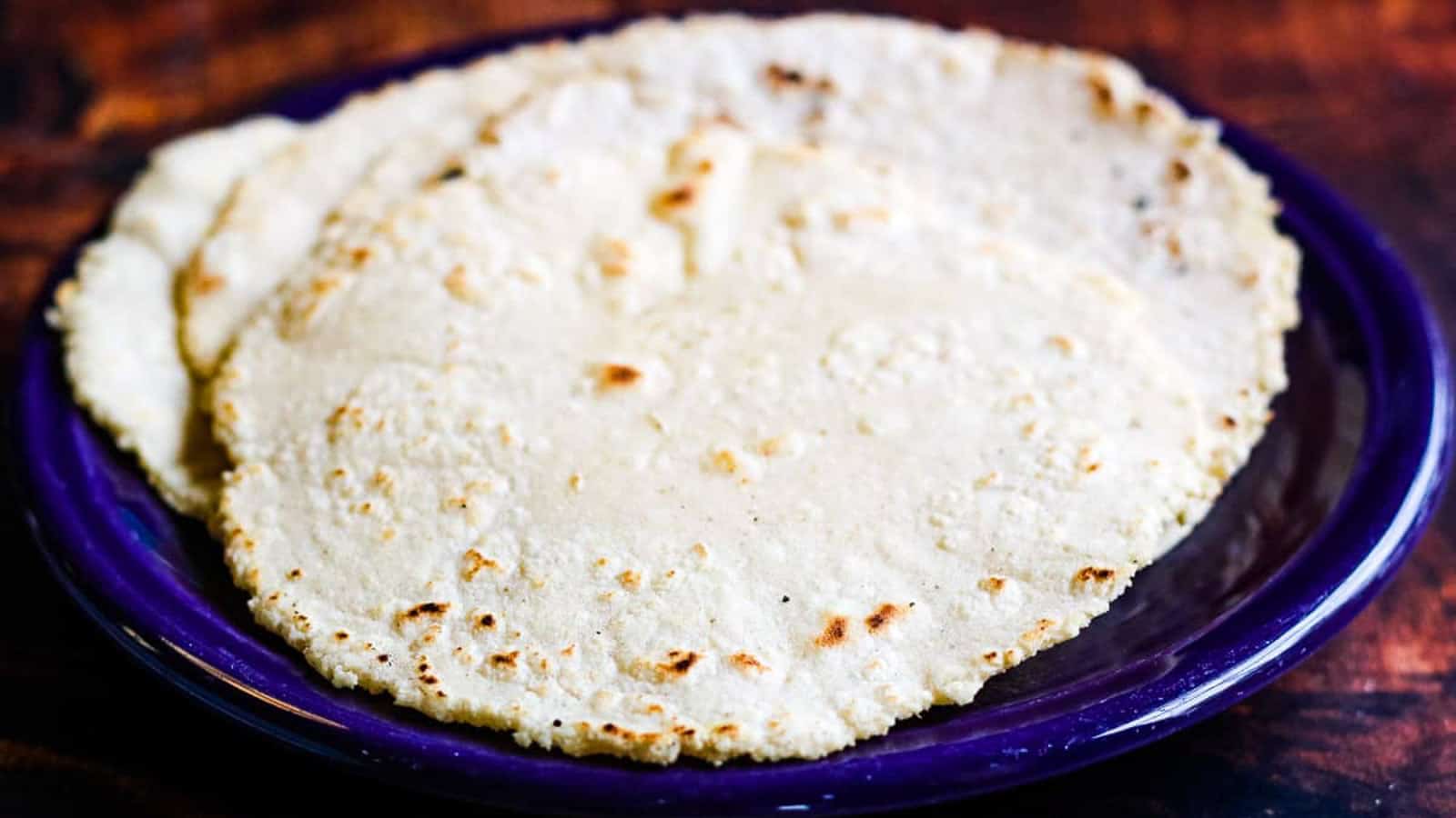 Stack of corn tortillas on a purple plate.