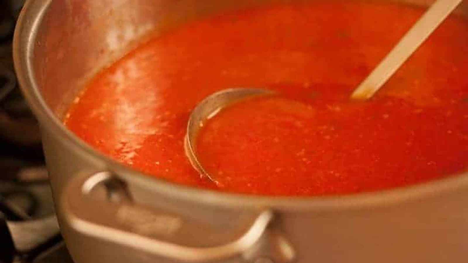 A pot of tomato soup with a ladle.